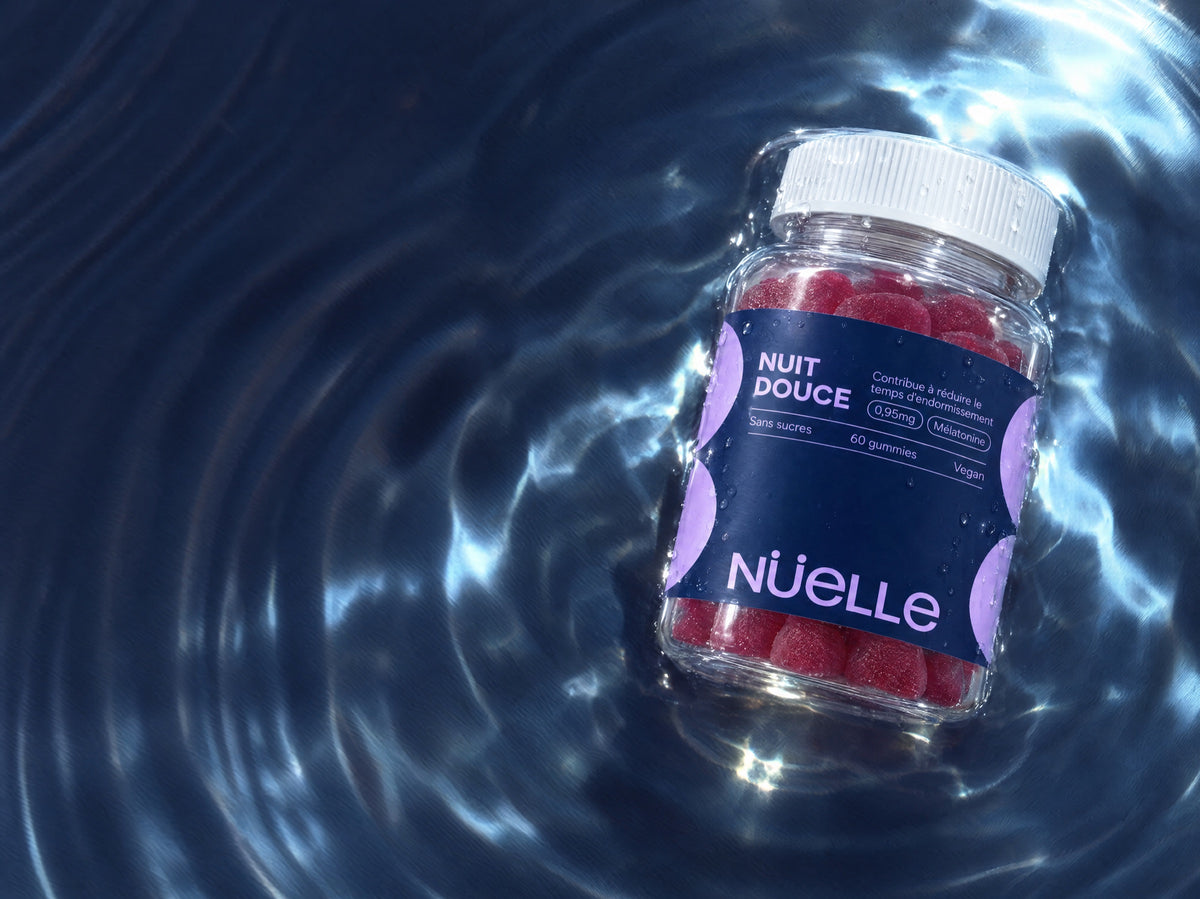 Pot de gommes NUIT DOUCE de NÜELLE posé dans une eau bleue aux reflets de lumière